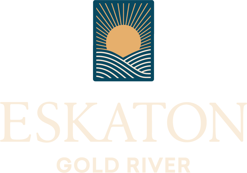 A logo with a stylized sun rising over wavy lines inside a rectangle, above the faded text ESKATON GOLD RIVER.