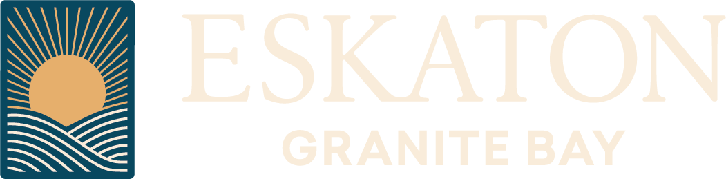 Logo for Eskaton Granite Bay featuring a stylized sun rising over waves in a blue square on the left, with ESKATON GRANITE BAY written in large, light beige letters to the right.